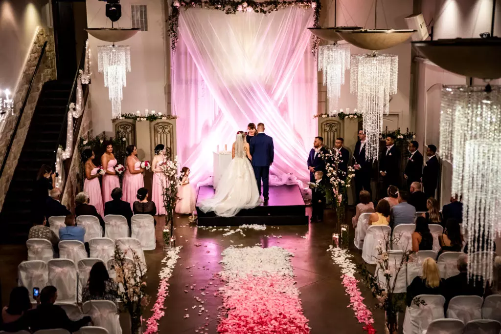 Indoor wedding ceremony with pink lighting